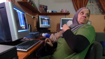 Person playing a computer game at a desktop PC with monitor, keyboard and mouse