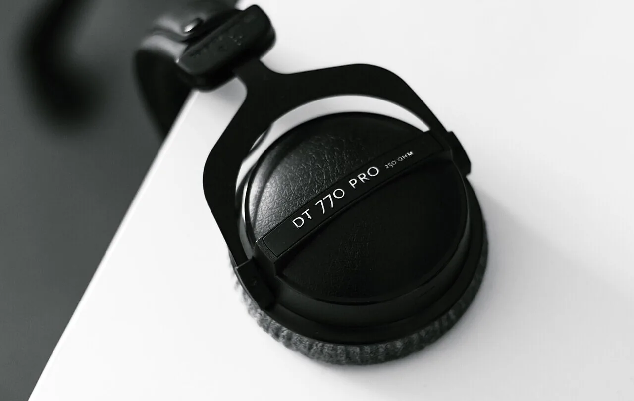 Black over-ear headphones hanging from the edge of a desk