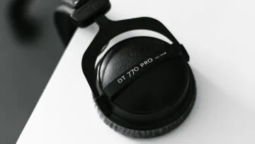 Black over-ear headphones hanging from the edge of a desk