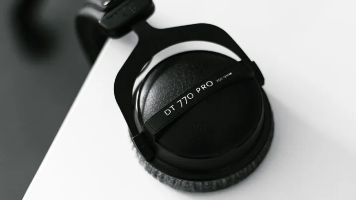 Black over-ear headphones hanging from the edge of a desk