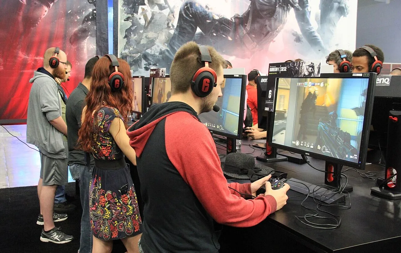 People playing PC games on desktop monitors at a gaming event