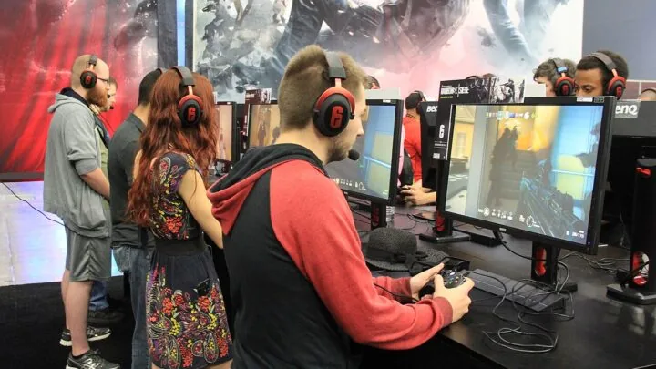 People playing PC games on desktop monitors at a gaming event